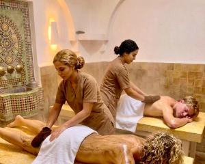a couple of women bathing a man in a bath tub at Hotel Al Alba Hammam & Restaurant in Asilah