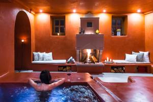 a woman sitting in a bath tub with a fireplace at Primoula Country Hotel & Spa in Ano Pedina