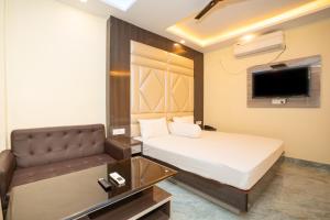 a bedroom with a bed and a couch and a tv at Mahabhoj Hotel & Restaurant in Mandarmoni