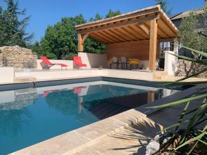 a swimming pool with a gazebo next to a house at Le Mazet, studio climatisé avec accès piscine in Saint Alban Auriolles