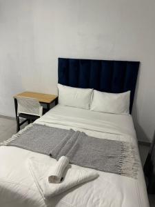 a bed with a blue headboard with a towel on it at Bell rose oaks guest house in Blomtuin