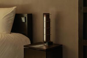 a lamp sitting on a night stand next to a bed at Achroma de Hanok in Seogwipo +53 photos
