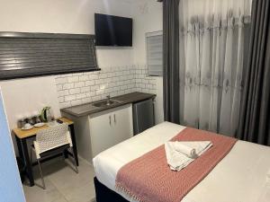 a small room with a bed and a sink at Bell rose oaks guest house in Blomtuin