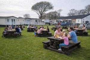 a group of people sitting at picnic tables in a park at Island Butterfly haven in Sandown