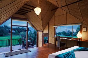 a room with a bed and a desk and windows at Jetwing Vil Uyana in Sigiriya