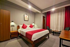 a bedroom with a bed with red pillows and a desk at Mayuri Lodge in Kalimpong