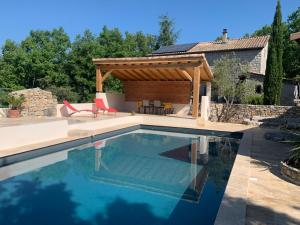 a swimming pool with a pergola next to a house at Chambre d'hôtes avec climatisation, terrasse privée et accès piscine in Saint Alban Auriolles