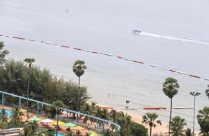 a boat in the water at a beach with palm trees at View Talay 3 Apartment in Pattaya South