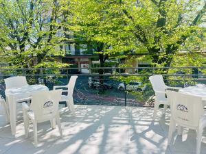 a patio with white tables and chairs and trees at Hotel Anversa Rimini in Rimini