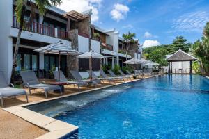 a pool at a hotel with chairs and umbrellas at Beachfront! 2 Bedroom Apartment A3 - 110 Sqm in Ko Lanta