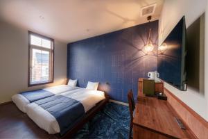 a bedroom with a bed and a blue wall at T9 Hakodate in Hakodate