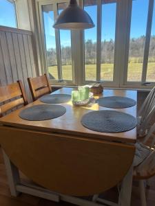 a dining room table with four chairs and a large window at Sommartornsgård in Munkedal +5 photos
