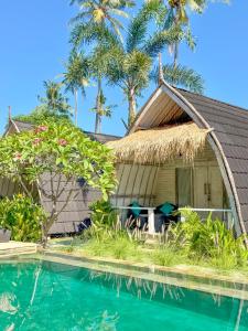 a house with a thatched roof next to a swimming pool at Gili Meno Escape - Adults Only in Gili Meno