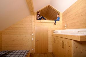 due persone sedute in cima a una casa di legno di Bio Chalet "Sonne" a Weisspriach