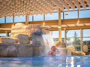 a man in a swimming pool with a waterfall at Altmühl Hideaway Apartment 1 in Treuchtlingen