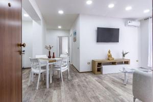 a dining room with a table and chairs and a tv at Blanche Apartments in Porto Torres
