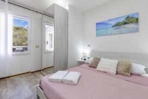 a white bedroom with a pink bed and a window at Blanche Apartments in Porto Torres