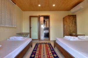 2 Betten in einem Zimmer mit einem Teppich in der Unterkunft Baba Veli Pension in Kaleucagız