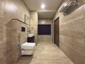 a bathroom with a toilet and a sink and a screen at Hotel Liora in Rajkot