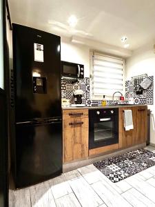 a kitchen with a black refrigerator and a sink at Au Cocon Alsacien in Wintzenheim