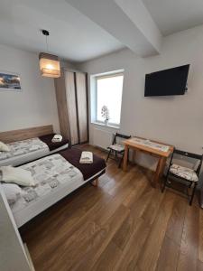 a room with two beds and a tv and a table at Apartamenty Bełska Centrum in Ustrzyki Dolne