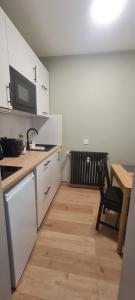 a kitchen with white cabinets and a table and a microwave at Studio proche Cathédrale in Autun