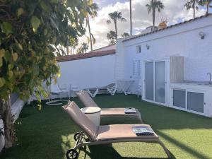 a patio with a lawn with chairs and a table at Suite Coco in Maspalomas