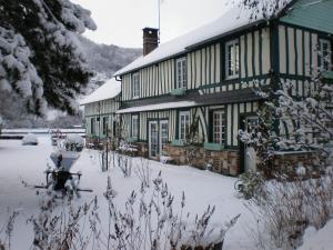 a building with snow on the ground in front of it at Chambre d'hôtes Au Fil De L'eau in Jumièges