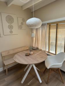 a dining room with a table and a white chair at Studio Oranje Nassau aan Zee in Zandvoort