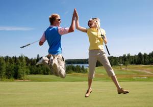 un hombre y una mujer saltando al aire mientras juegan al golf en Revontuli Resort Rooms, en Hankasalmi