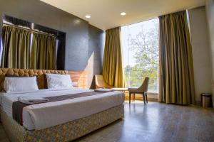 a bedroom with a bed and a chair and a window at Shubhham Regency in kolkata