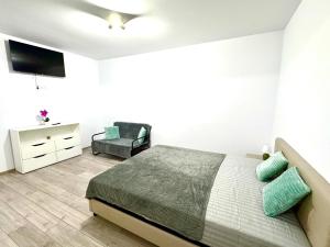 a white bedroom with a bed and a chair at Servio apart in Otopeni