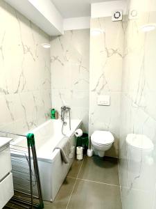 a white bathroom with a tub and a toilet at Servio apart in Otopeni
