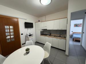 a kitchen with a table and white cabinets and a room at Appartamenti al Cigno in Lignano Sabbiadoro