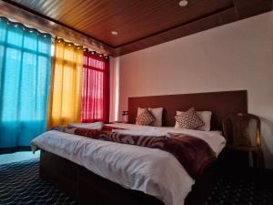 a bedroom with a large bed with colorful curtains at pangong rainbow cottage in Lukung