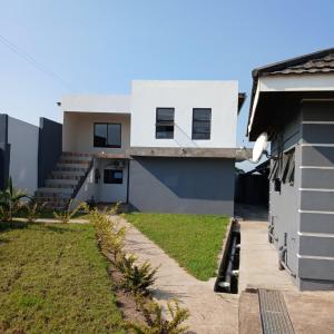 a white house with a yard next to a building at Likhanyile Guest Lodge in Nhlangano
