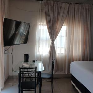 a bedroom with a table and a bed and a window at Likhanyile Guest Lodge in Nhlangano