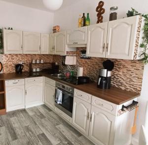 a kitchen with white cabinets and a wooden floor at Familienfreundliche Fewo mit Garten in Schwarz