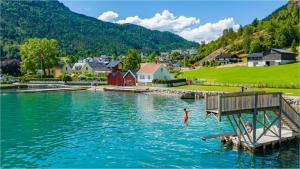 a person swimming in the water near a village at Molden Sky - takterrasse med egen jacuzzi! in Luster