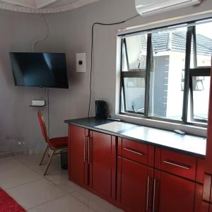 a living room with a red cabinet and a window at Likhanyile Guest Lodge in Nhlangano