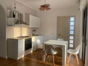 a kitchen with a white table and chairs and a table and a stove at A casa di Chiara in Isca sullo Ionio