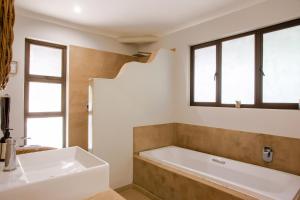 a bathroom with a tub and a sink and windows at Kingfisher Creek Safari Cottages in Hoedspruit +40 photos
