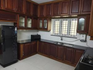 a kitchen with wooden cabinets and a black refrigerator at HK villas in Edappally