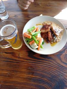 a plate of food with vegetables and a glass of beer at Fast food in Lukla