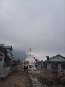 a group of people standing around a building with a lighthouse at Fast food in Lukla