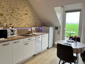 a kitchen with white cabinets and a table with a tableablish at La Suite Etoilée - Balnéo privative in Courgains