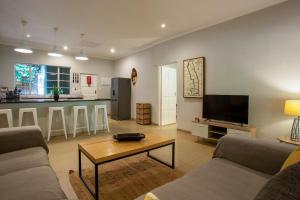a living room with a couch and a table and a kitchen at Kingfisher Creek Safari Cottages in Hoedspruit
