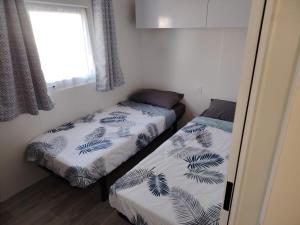 two beds in a small room with a window at MOBIL-HOME "B30" tout confort avec piscine & lave-linge gratuit in Mimizan +25 photos