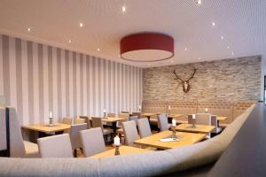a restaurant with wooden tables and chairs and a brick wall at Hotel Wildpferd Dülmen in Dülmen