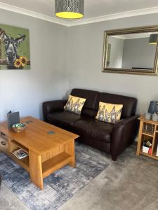a living room with a leather couch and a table at Silvermead stables Own access studios near Plymouth Life Centre FREE parking in Plymouth